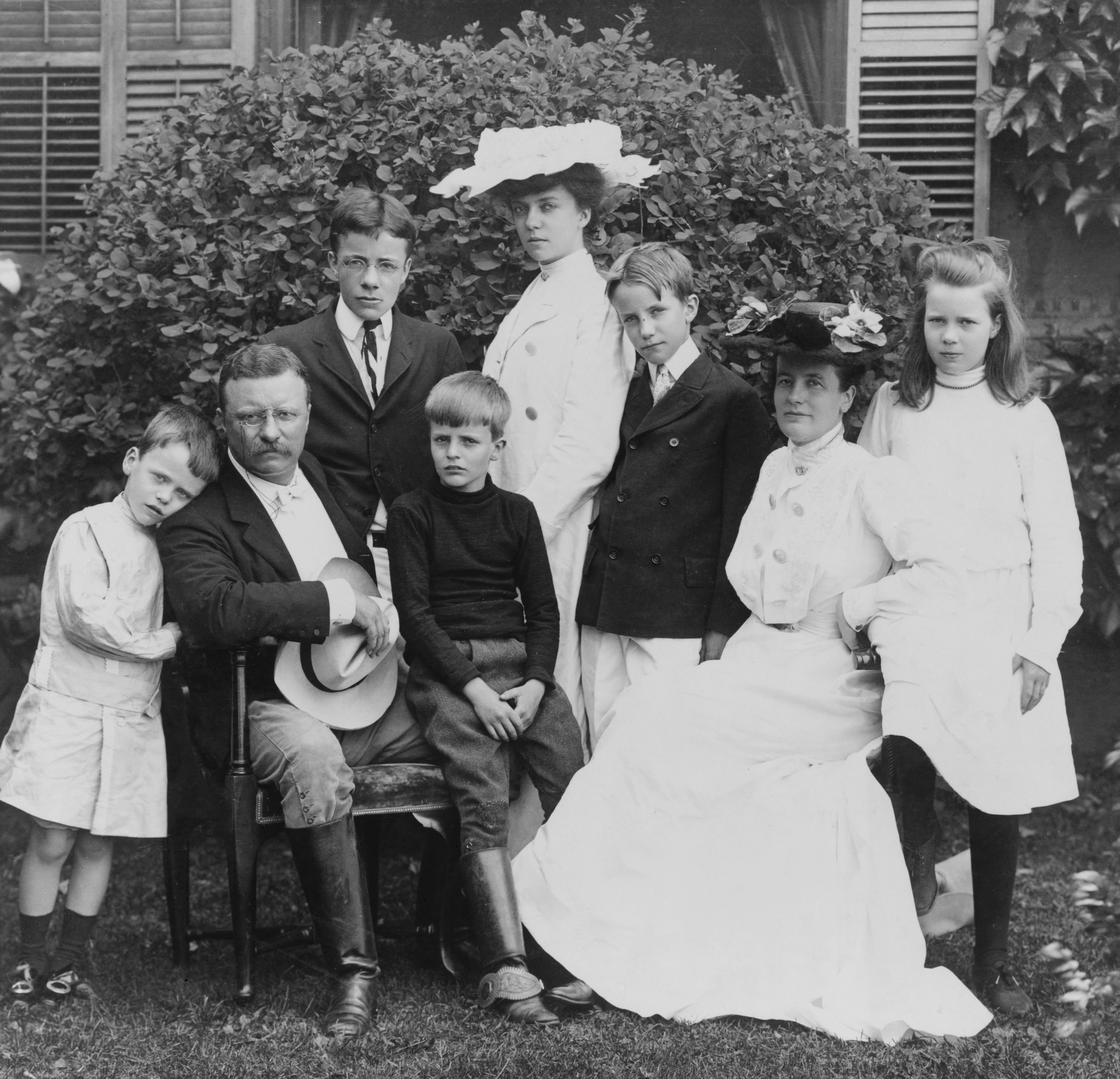 Pres. and Mrs. Theodore Roosevelt seated on lawn, surrounded by their family; 1903. From left to right: Quentin, Theodore Sr., Theodore Jr., Archie, Alice, Kermit, Edith, and Ethel. (public domain through US National Library of Congress= 